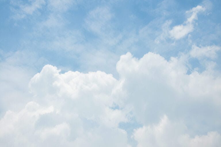 Fluffy white clouds scattered across a bright blue sky, creating a serene and tranquil atmosphere.