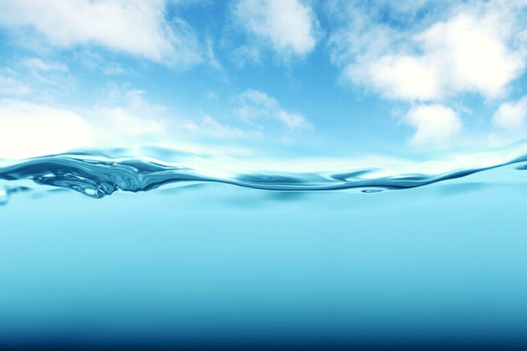 blue sky with clouds on top half of frame, crisp, fresh water on the bottom half of frame