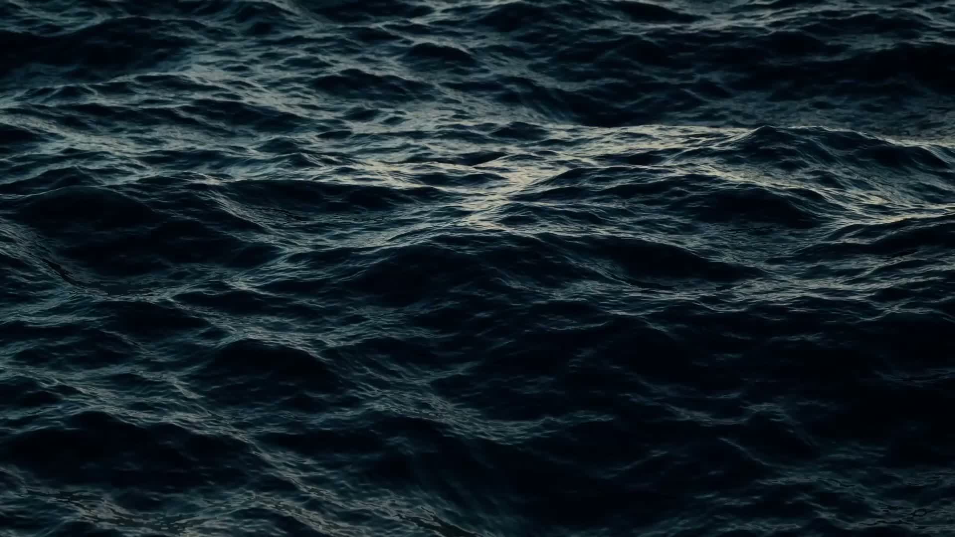 Dark, rippling ocean waves reflecting subtle light, creating a serene and moody atmosphere.