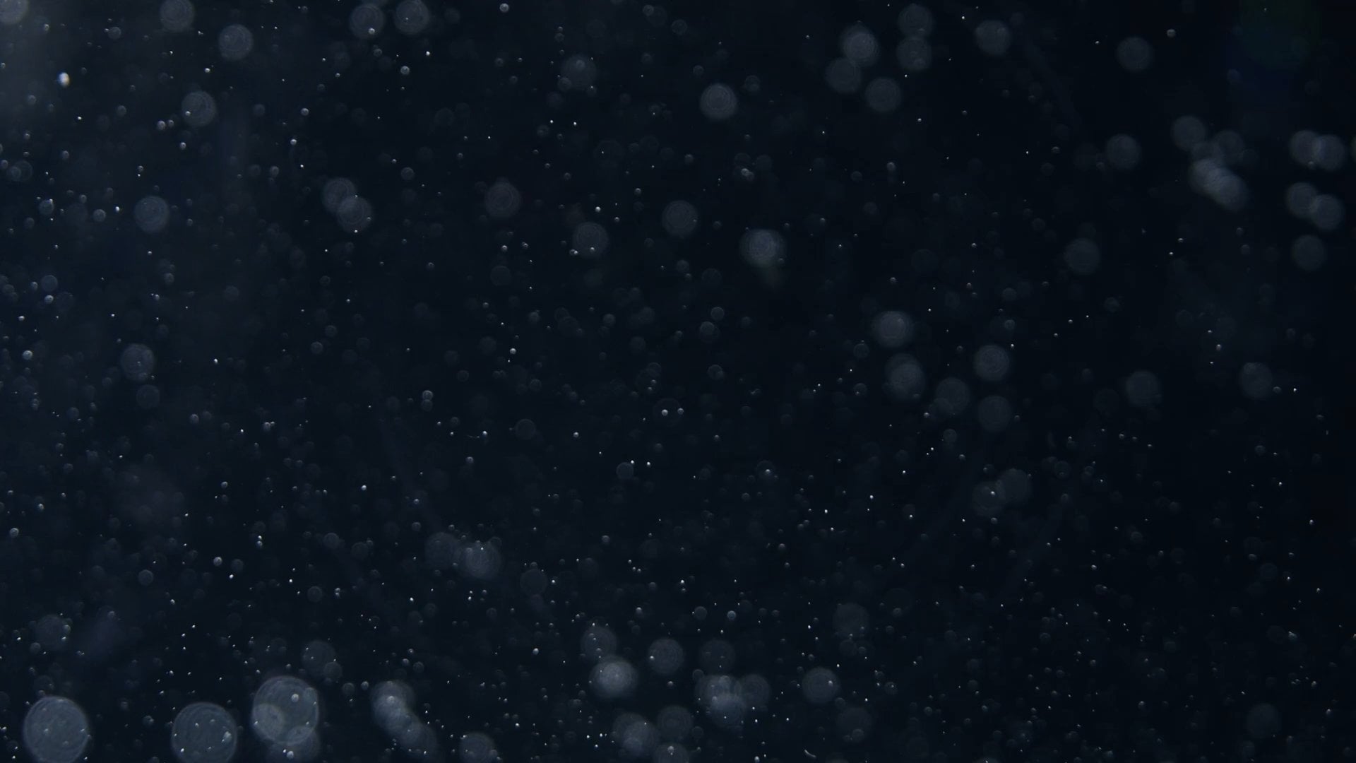 Dust particles floating in dark space with soft bokeh lights.
